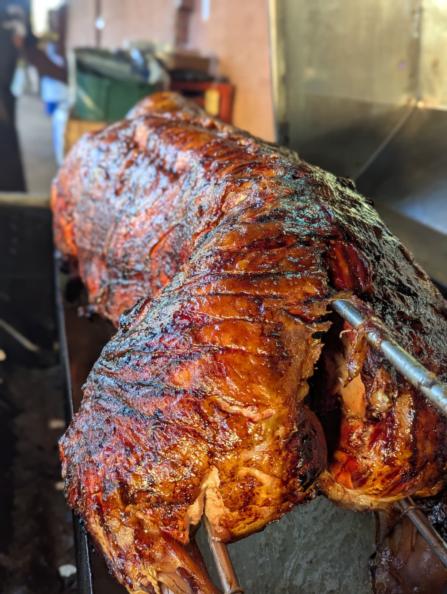 Golden spit-roasted whole lamb turning over the fire